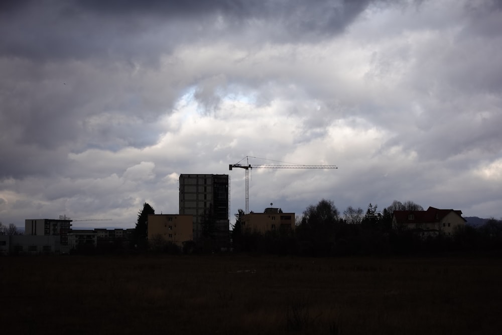 a building under a cloudy sky with a crane in the distance