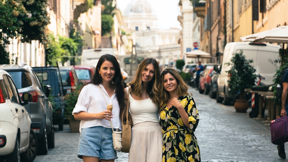 Tres mujeres están paradas en medio de una calle