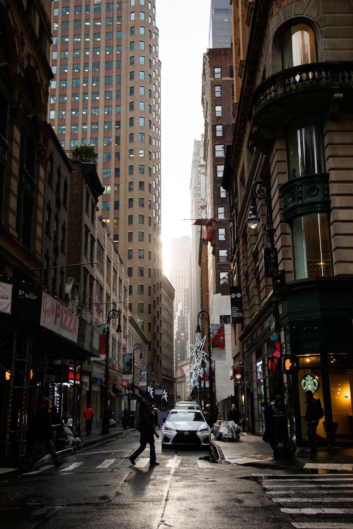 Man walking across a city street next to tall buildings