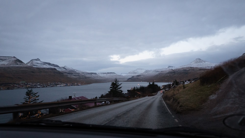 a car driving down a road next to a lake