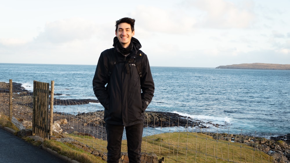 a man standing on the side of a road next to the ocean