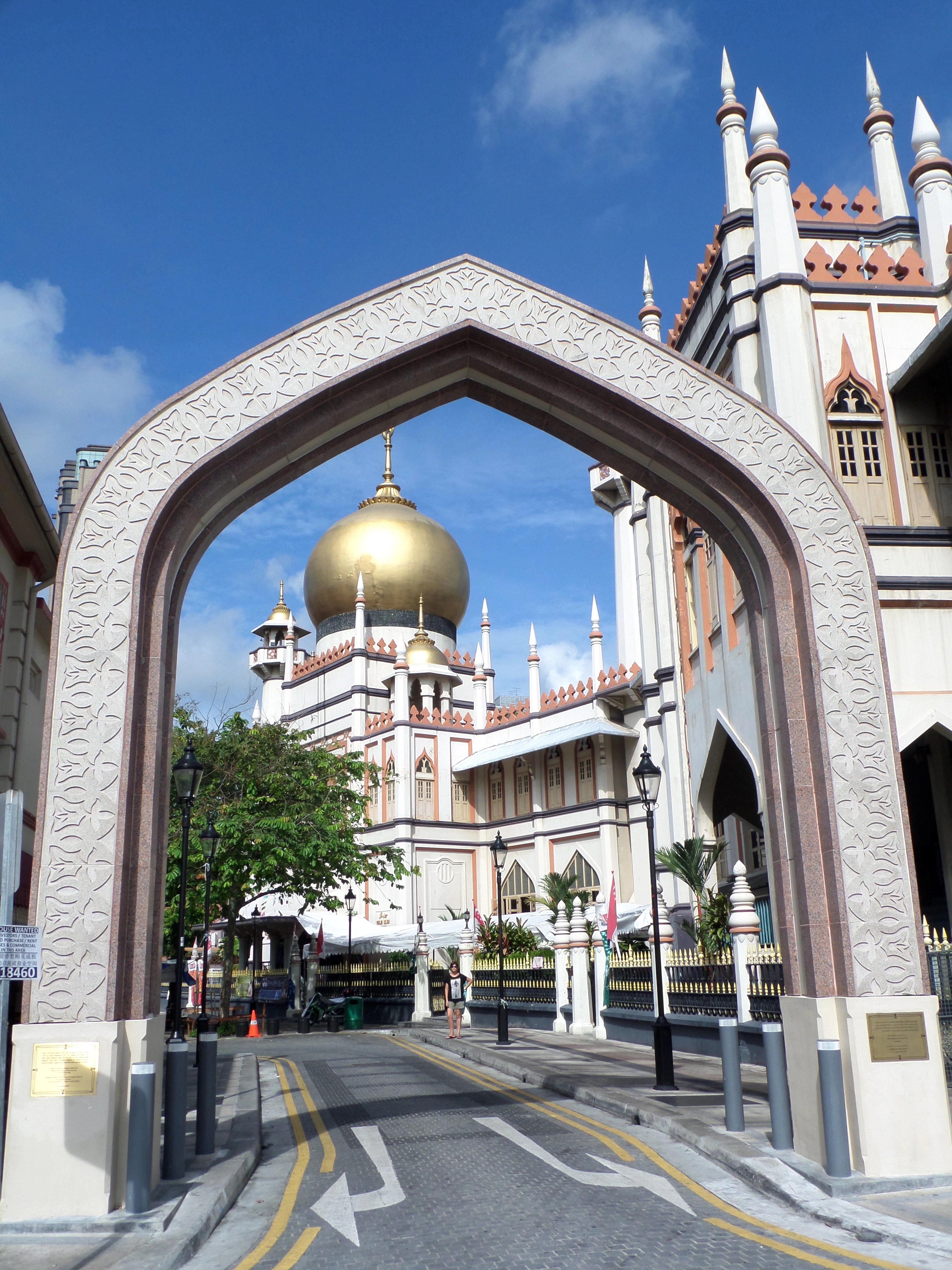 The golden dome and white minarets of Masjid Sultan framed by a street archway in Kampong Glam, Singapore