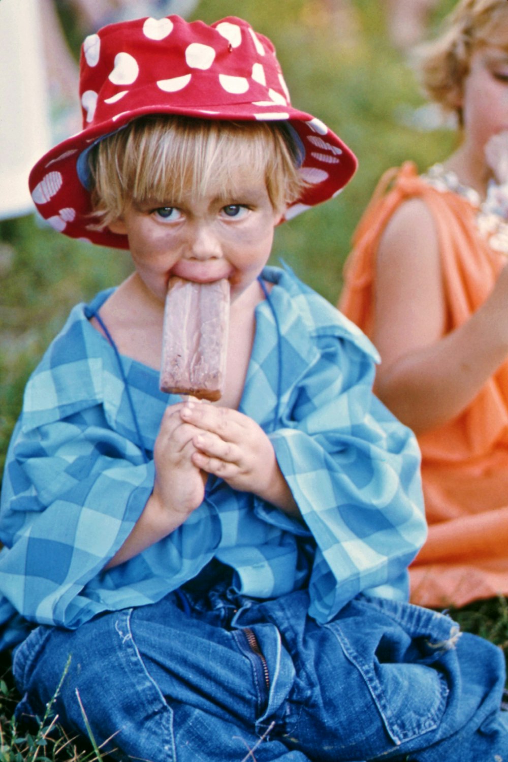 a little boy sitting on the ground eating a piece of food