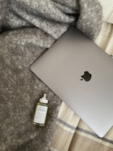 A cozy workspace with a laptop, a bottle of perfume, and soft natural light.