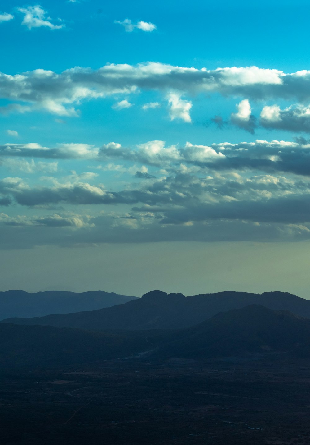 a plane flying over a mountain range under a cloudy sky