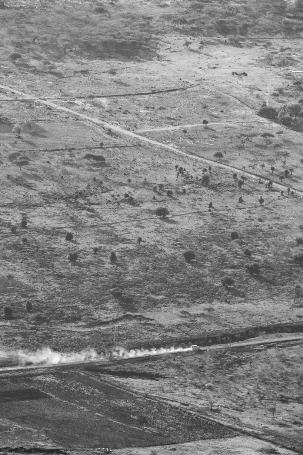 a black and white photo of a plane flying over a field