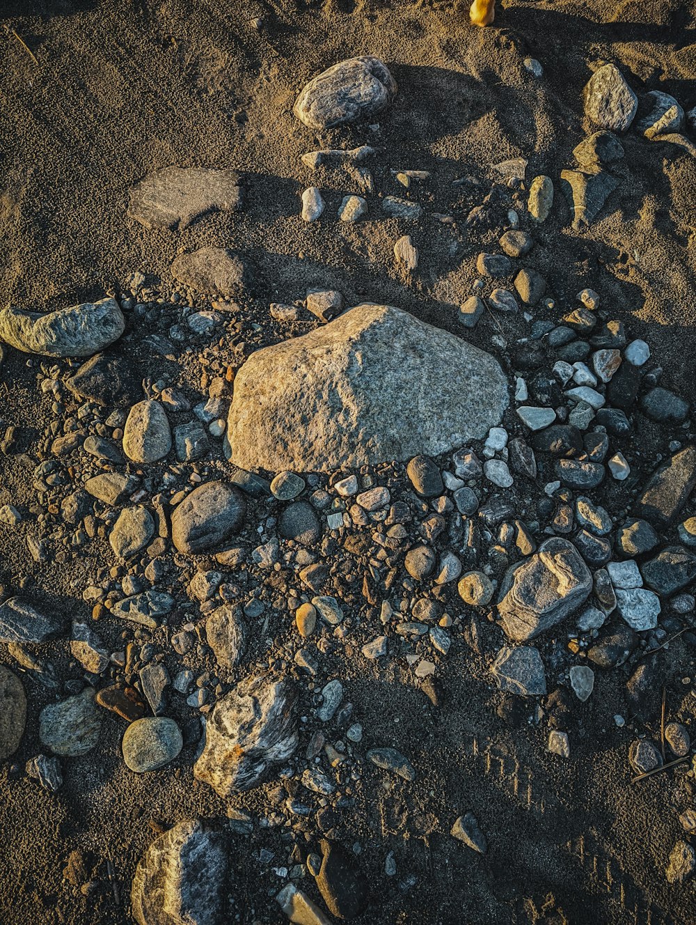 rocks and gravel on the ground with a yellow object in the middle