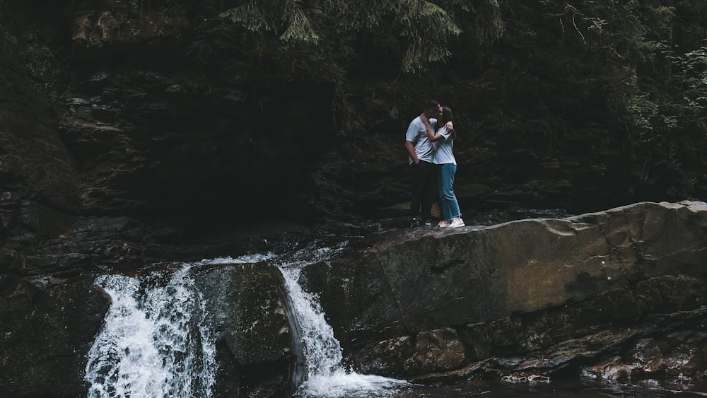 a man standing on a rock next to a waterfall