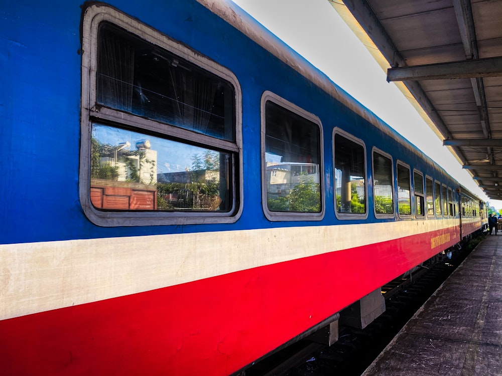 a red, white, and blue train stopped at a train station