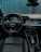 A modern car interior featuring a sleek, black dashboard with digital displays and controls. There's a prominent steering wheel with an Audi logo, and the seats are upholstered in black leather with red stitching. The overall design is high-tech and ergonomic.