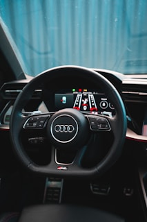 A car interior featuring a sleek, modern steering wheel with numerous controls and a digital dashboard display. The design is sophisticated, with a focus on comfort and technology.