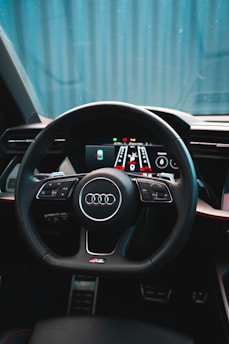 A car interior featuring a sleek, modern steering wheel with numerous controls and a digital dashboard display. The design is sophisticated, with a focus on comfort and technology.