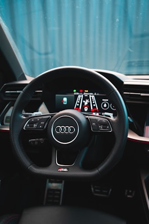 A car interior featuring a sleek, modern steering wheel with numerous controls and a digital dashboard display. The design is sophisticated, with a focus on comfort and technology.