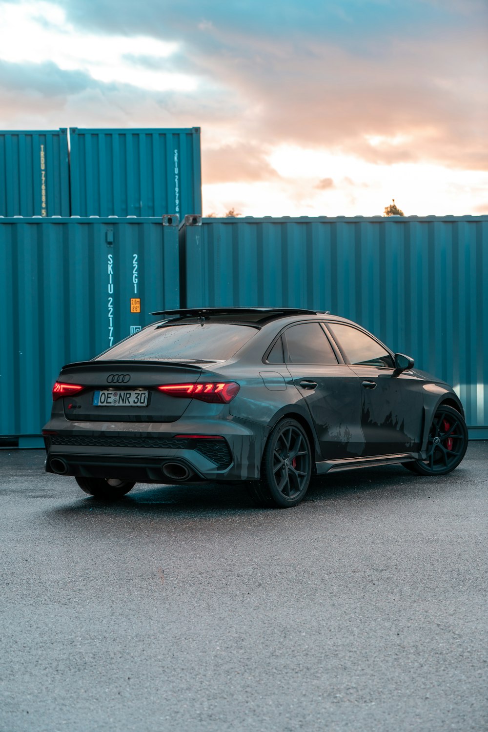 a grey car parked in front of a blue container