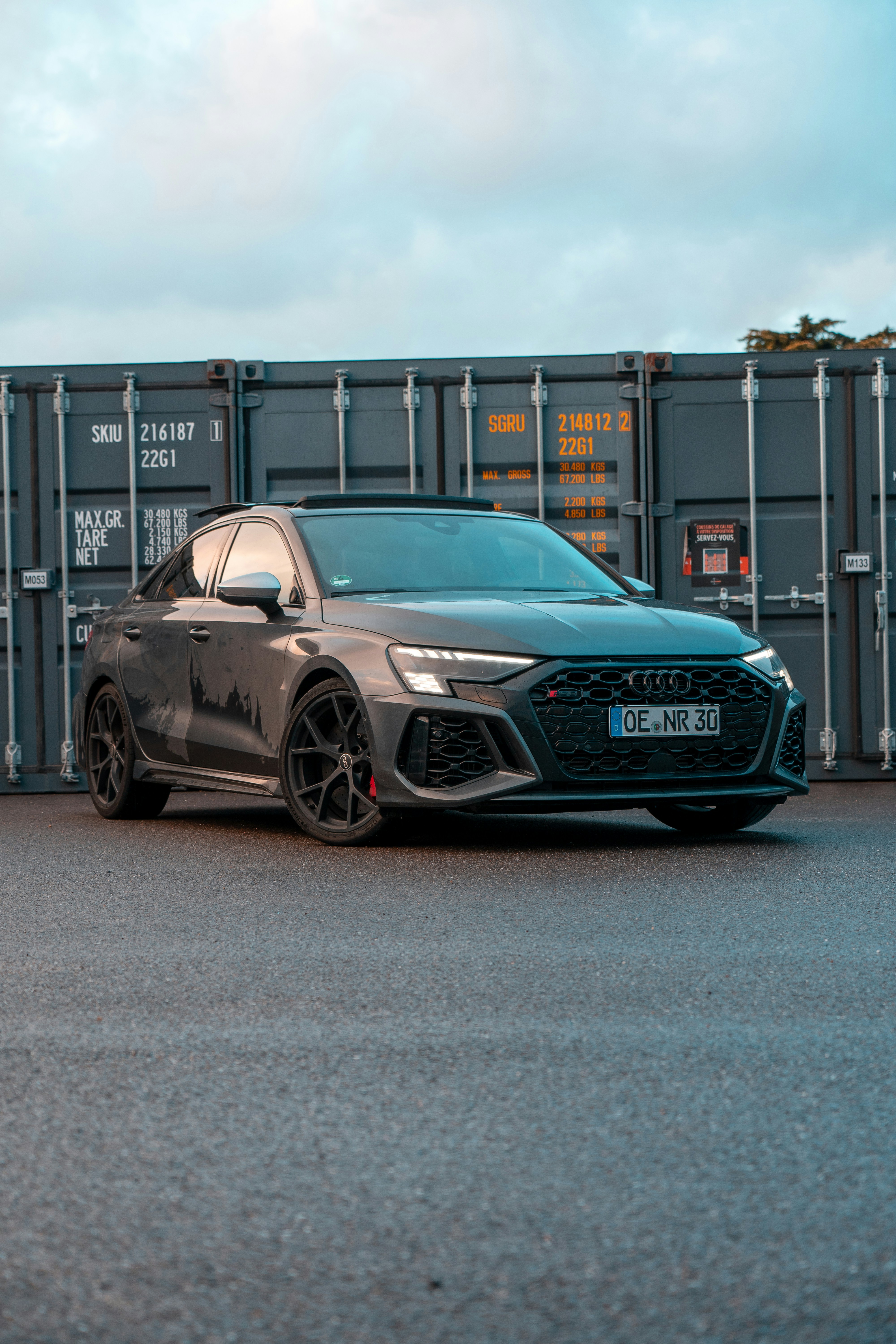 a grey car parked in front of a shipping container
