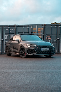 a grey car parked in front of a shipping container