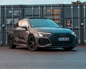 a grey car parked in front of a shipping container