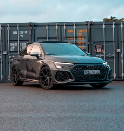 a grey car parked in front of a shipping container