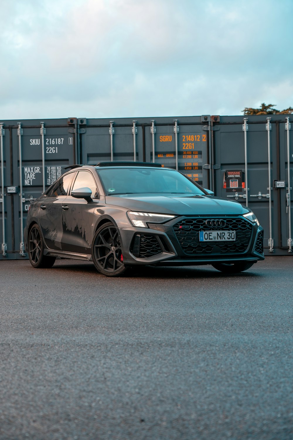 a grey car parked in front of a shipping container