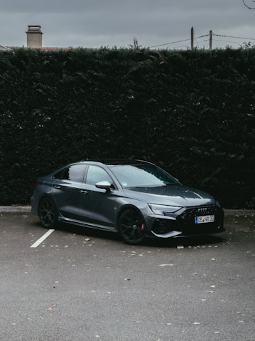 a car parked in a parking lot next to a hedge