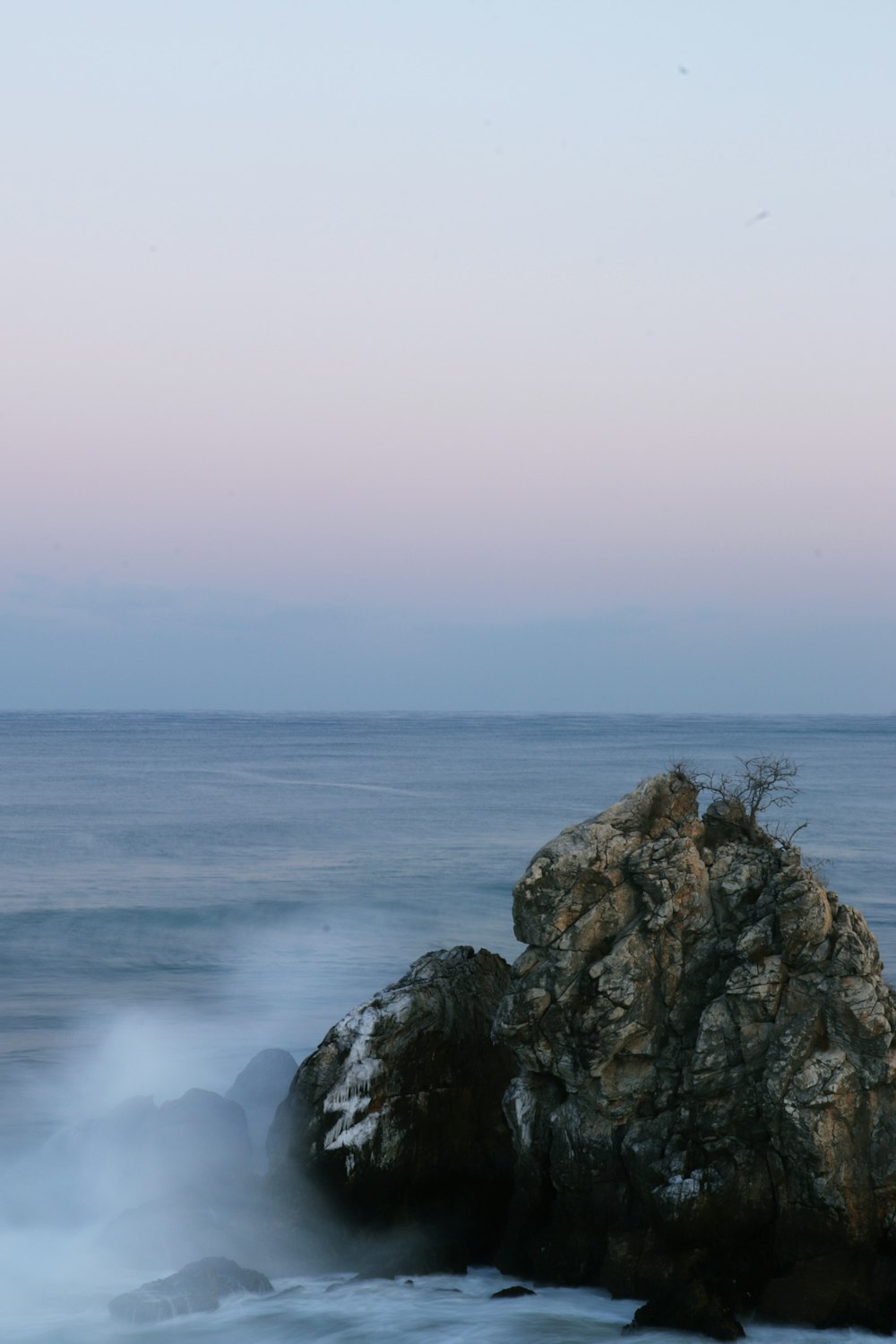 a large rock sitting on top of a beach next to the ocean