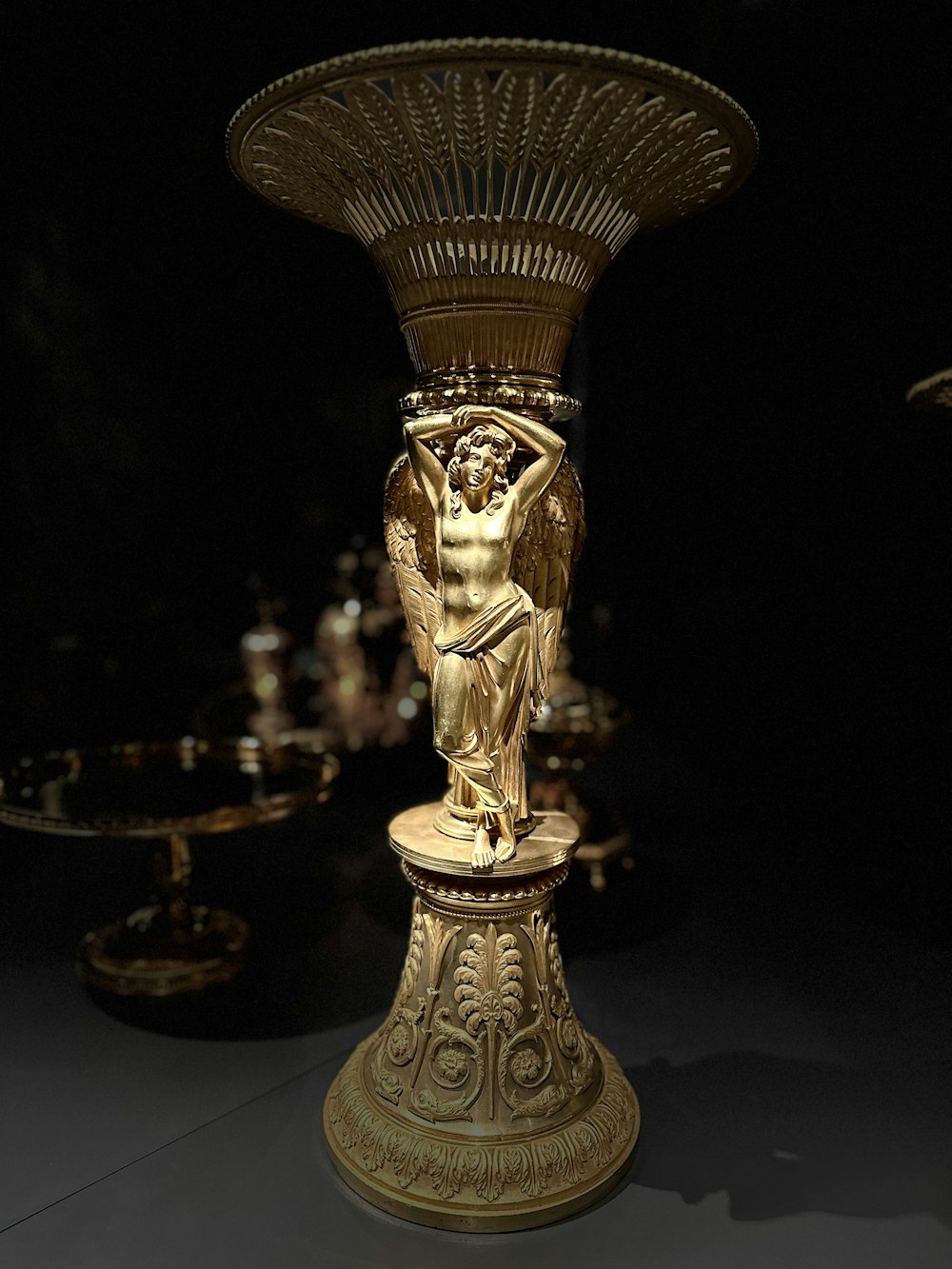 a gold statue of a woman holding a vase