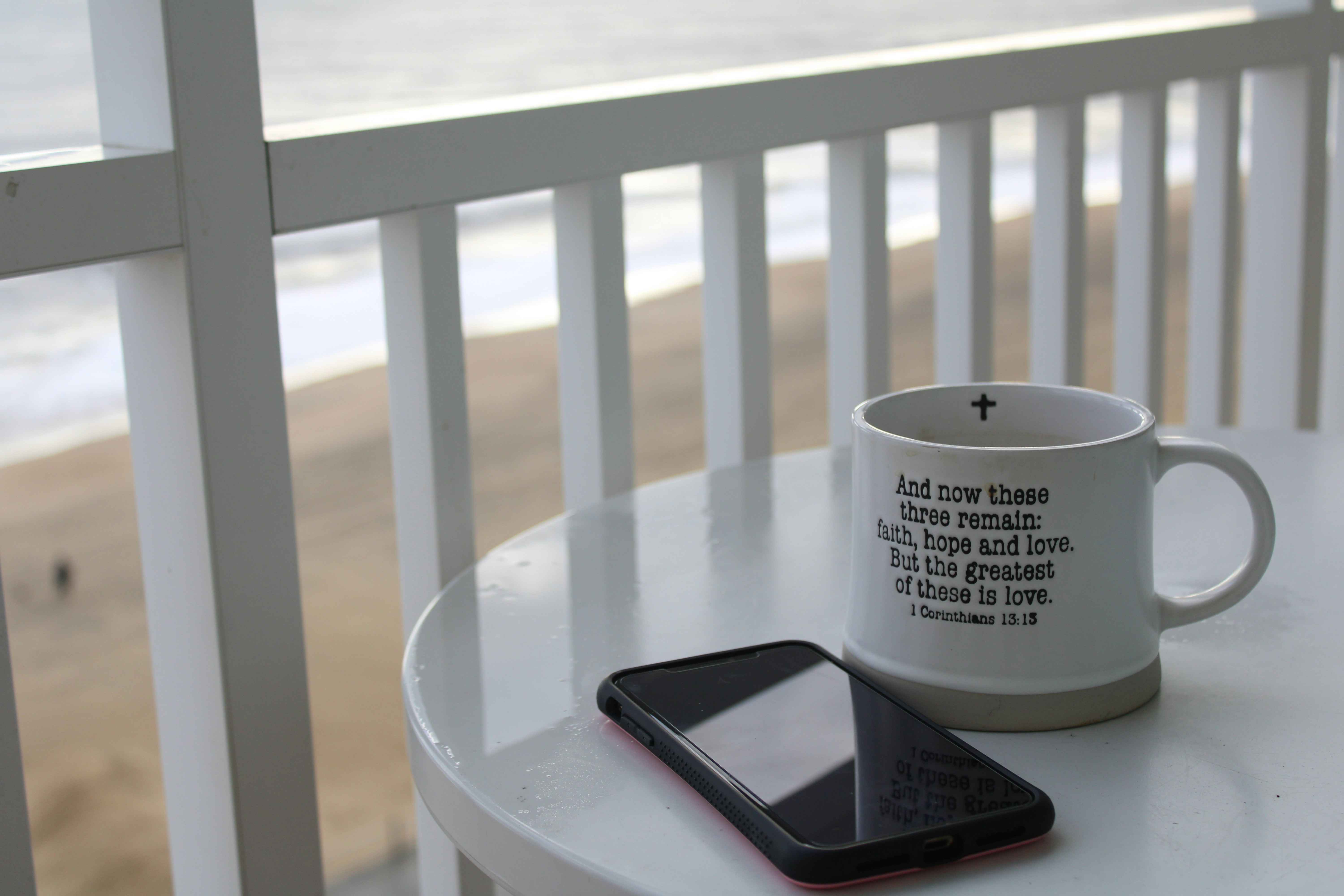 Um belo amanhecer com uma xícara de café e um celular exibindo uma mensagem de bom dia.