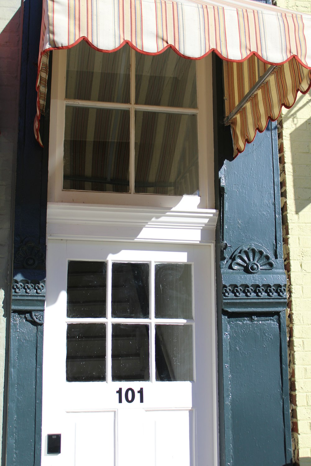 a white door with a striped awning over it