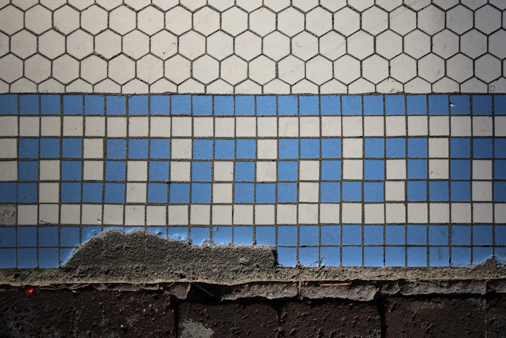 a blue and white tiled wall next to a brick wall