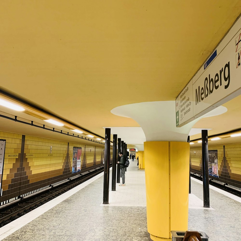 a subway station with a sign and a woman sleeping on the floor