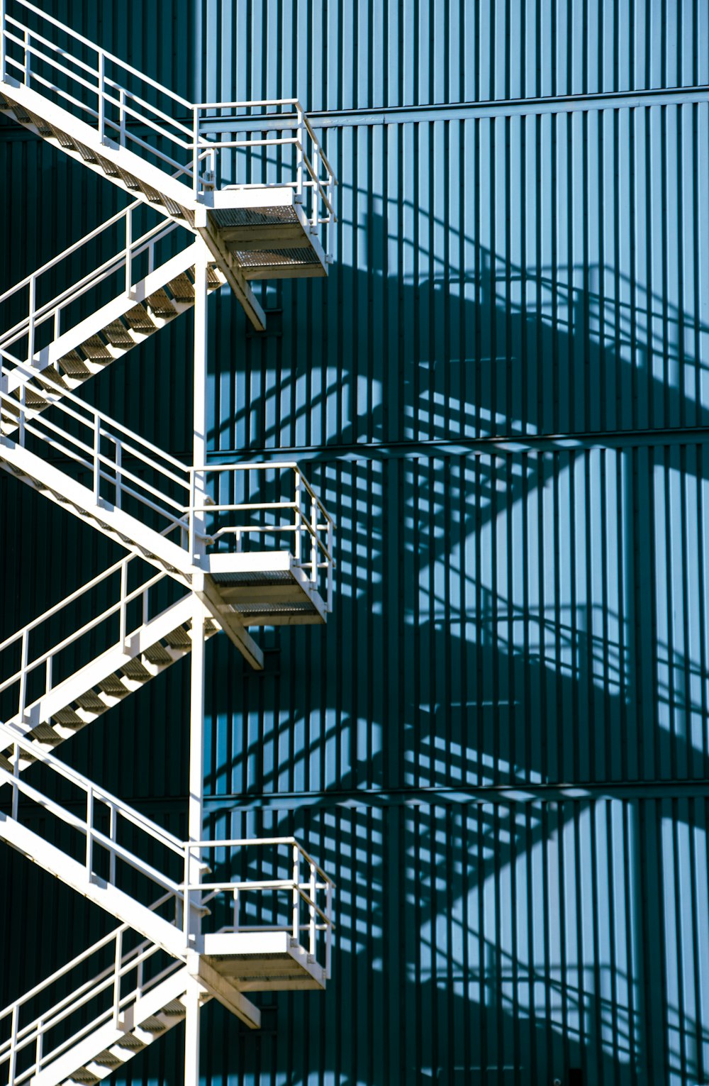 a metal staircase next to a building with a blue sky in the background