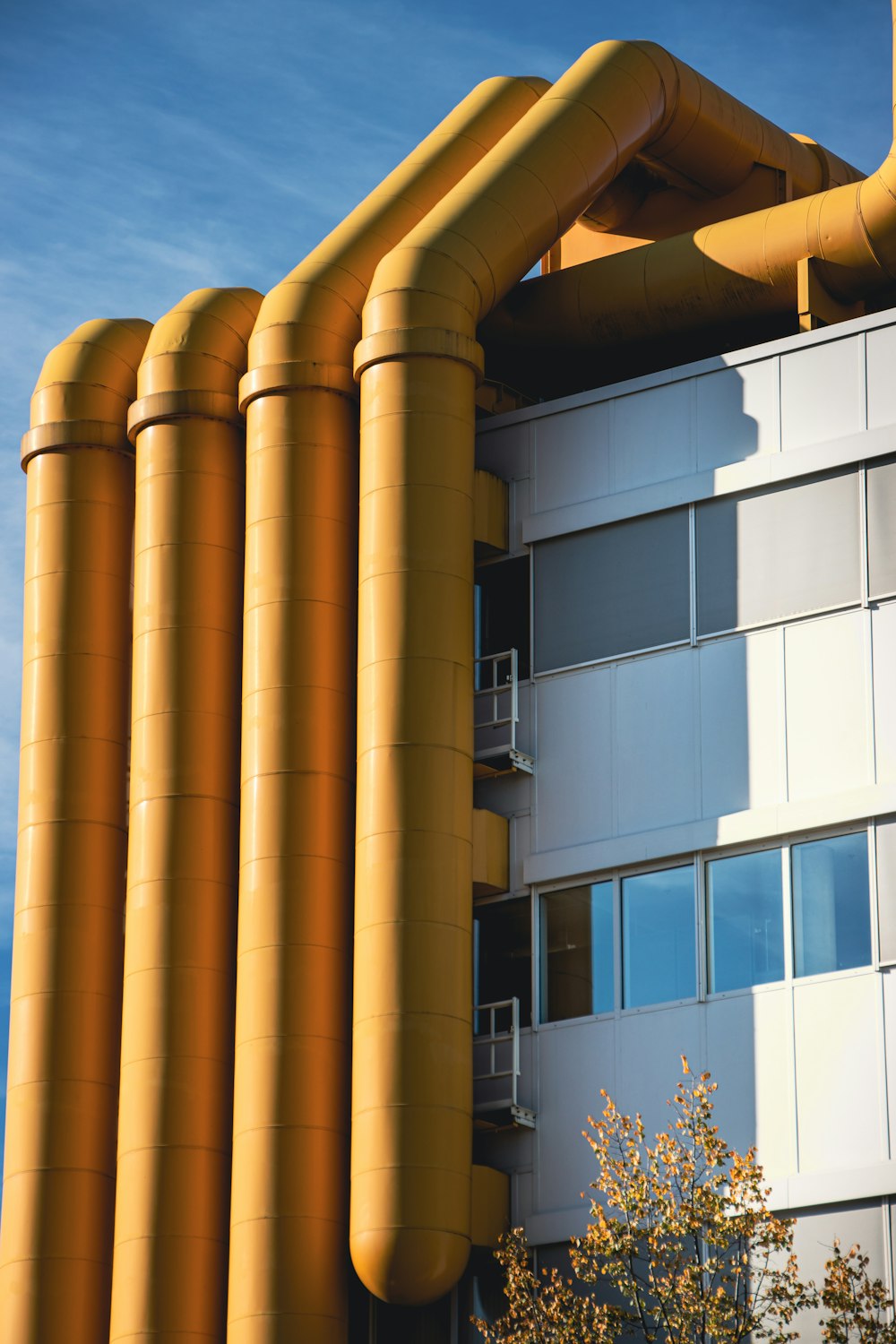 a tall building with a bunch of yellow pipes on top of it