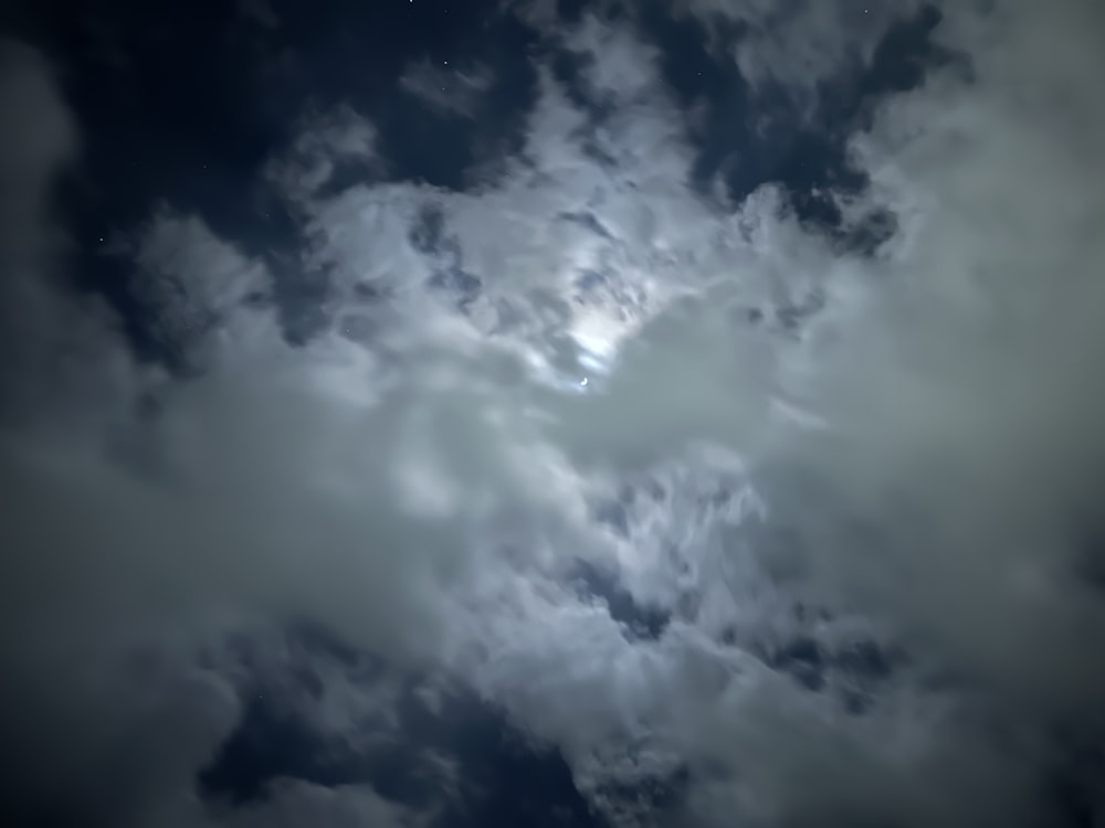 a very cloudy sky with a bright moon in the middle