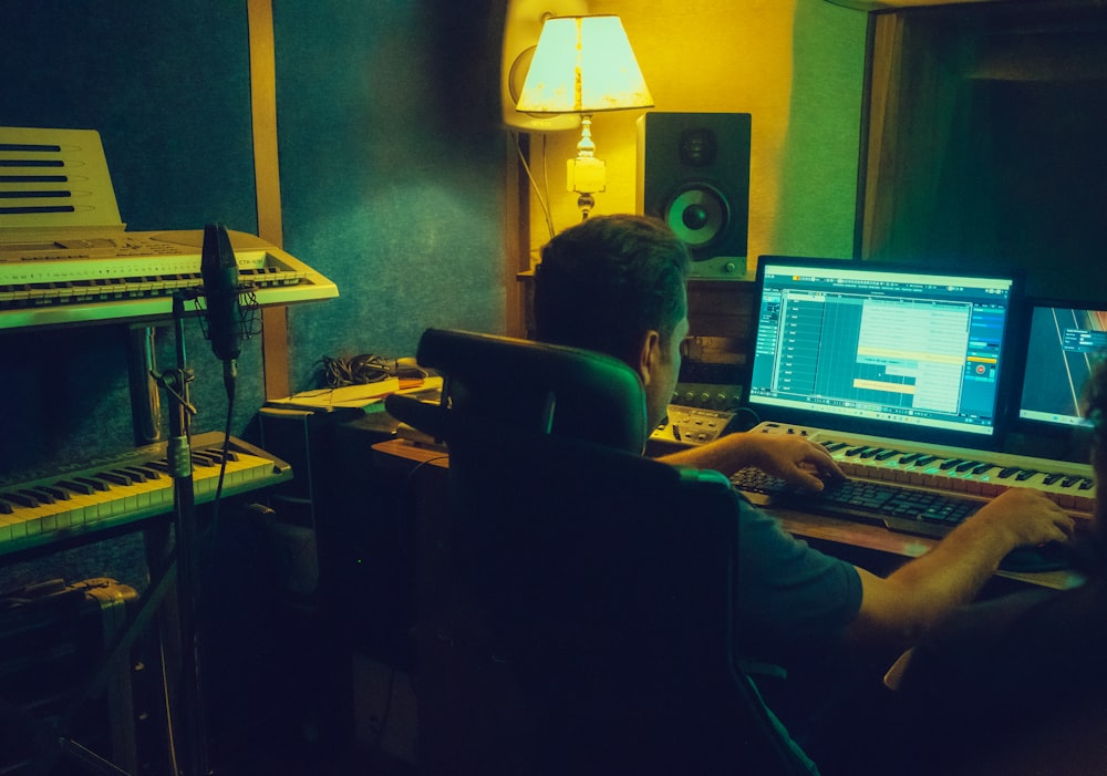 a man sitting in front of a computer in a recording studio