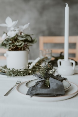 A minimalist dining table set with elegant tableware and a centerpiece of seasonal greenery.