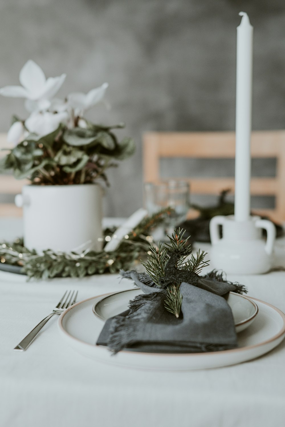 a place setting with a candle, napkin, and flowers