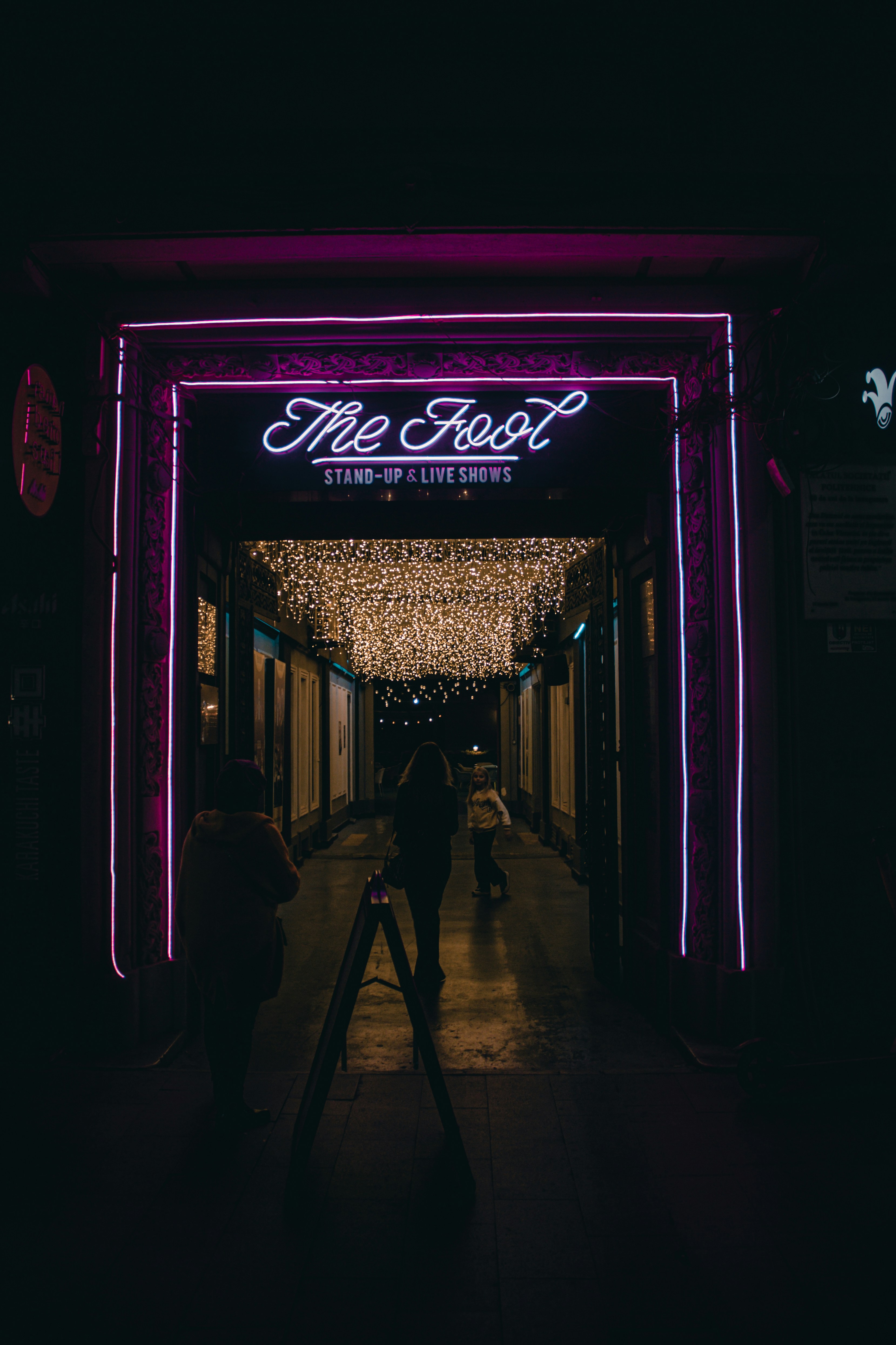 a couple of people that are walking under a neon sign