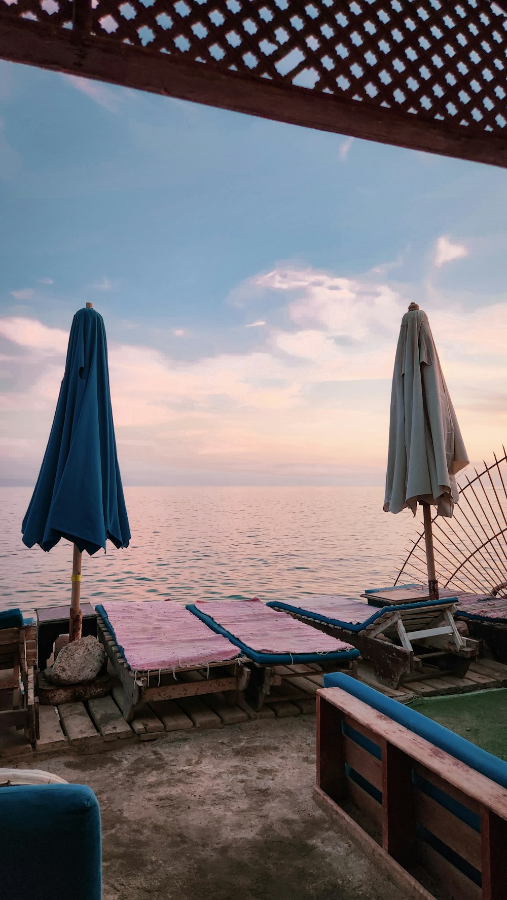 a view of the ocean from a deck with chairs and umbrellas