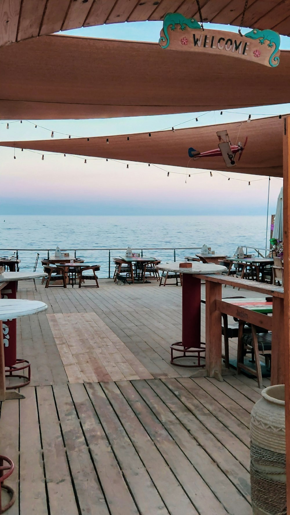 a wooden deck with tables and umbrellas overlooking the ocean