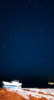 A peaceful night scene showing stars reflected on the water around the anchored boat.