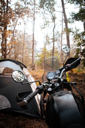 a motorcycle parked next to a tent in the woods