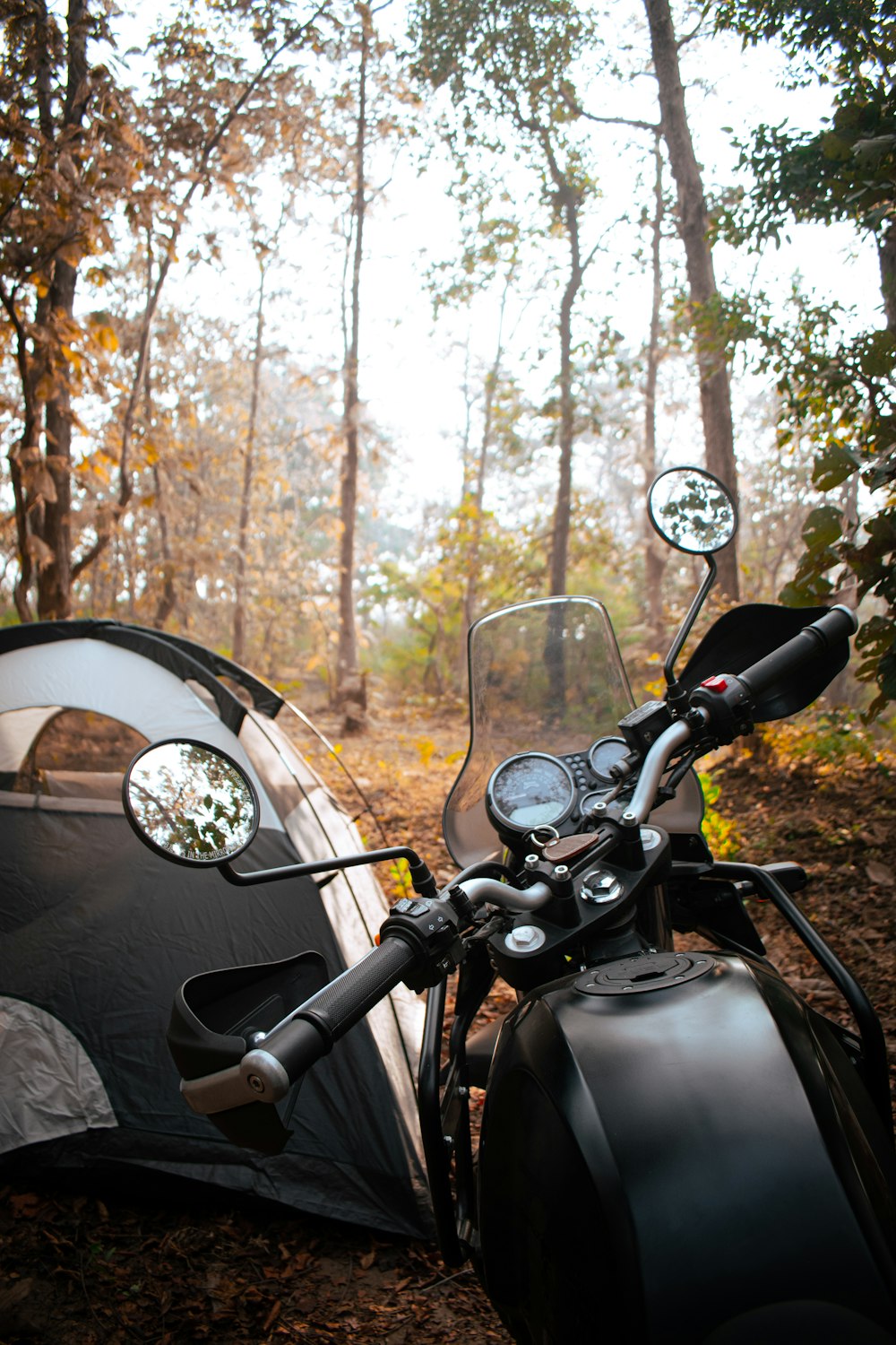 a motorcycle parked next to a tent in the woods