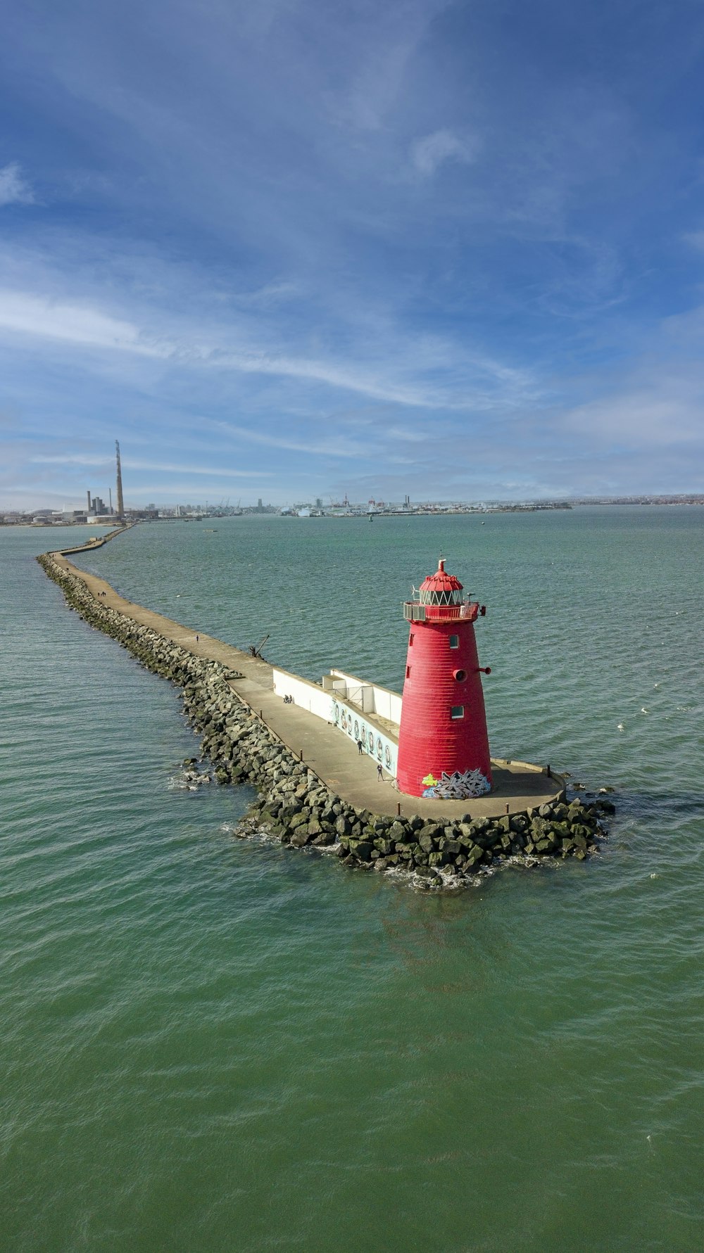 a red and white lighthouse in the middle of the ocean