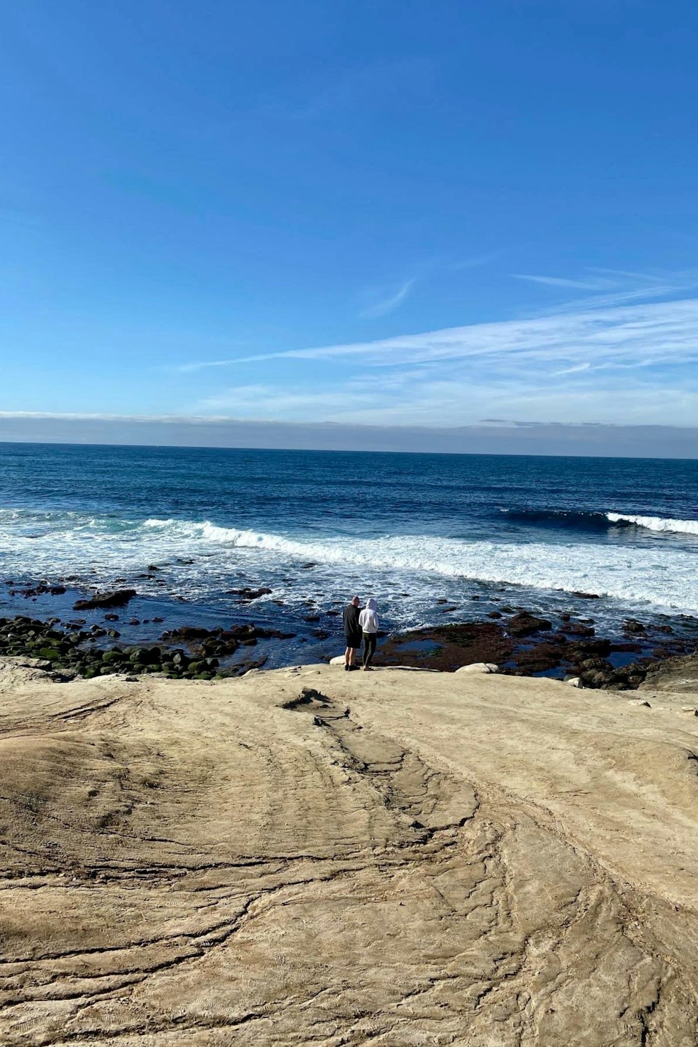 a couple of people standing on top of a sandy beach