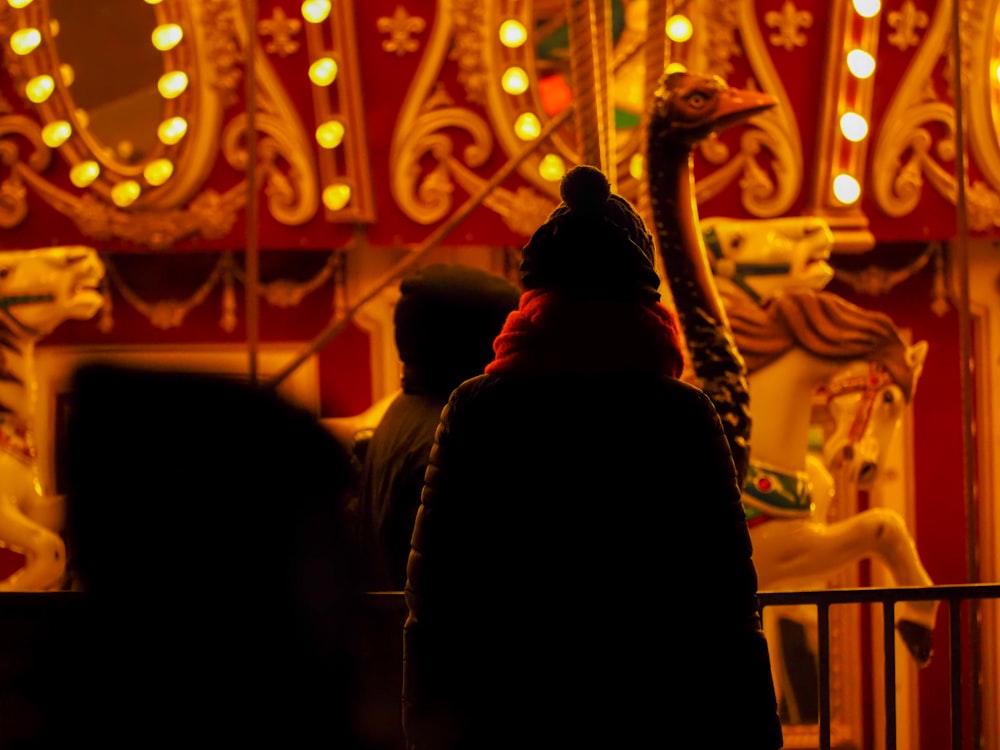 a person standing in front of a carousel at night