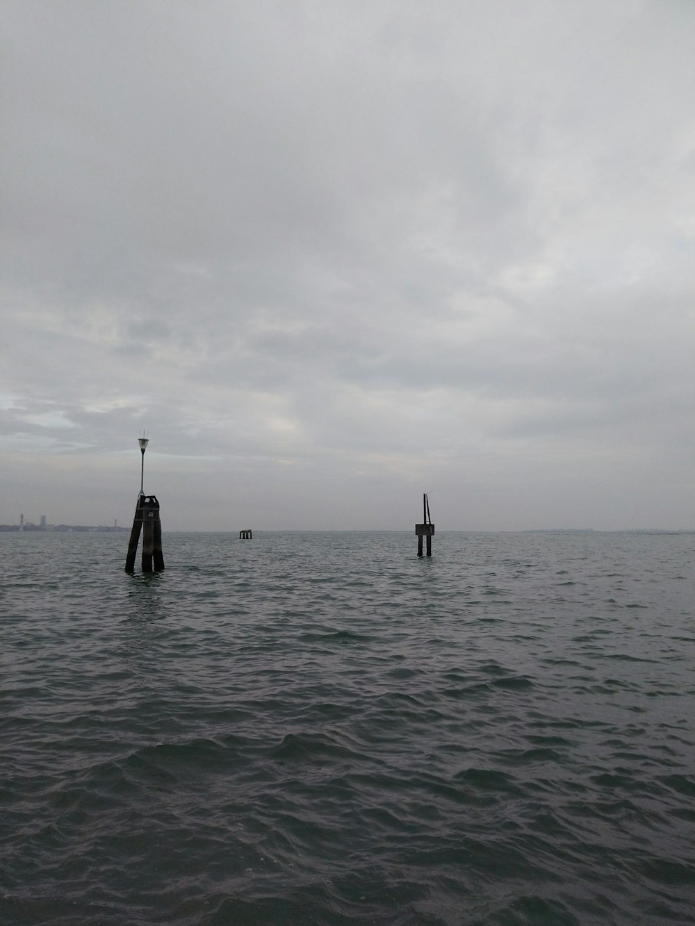two poles sticking out of the water on a cloudy day