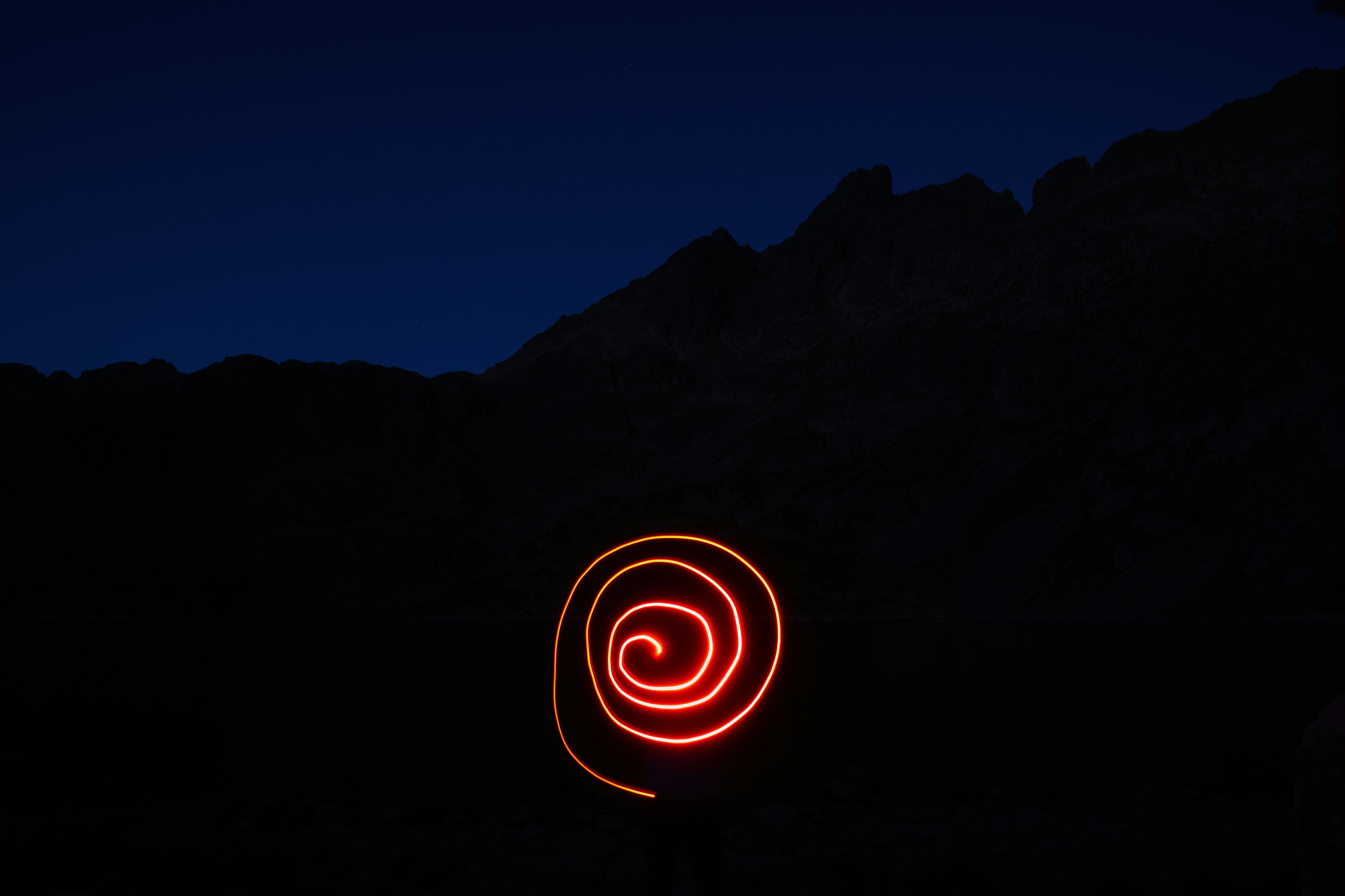 a red light in the dark with a mountain in the background