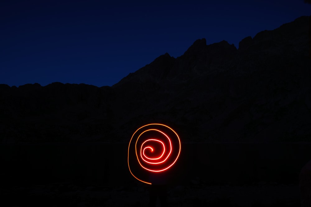 a red light in the dark with a mountain in the background