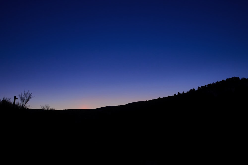 a silhouette of a person standing on top of a hill