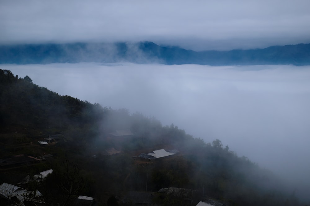 a foggy mountain with houses in the foreground